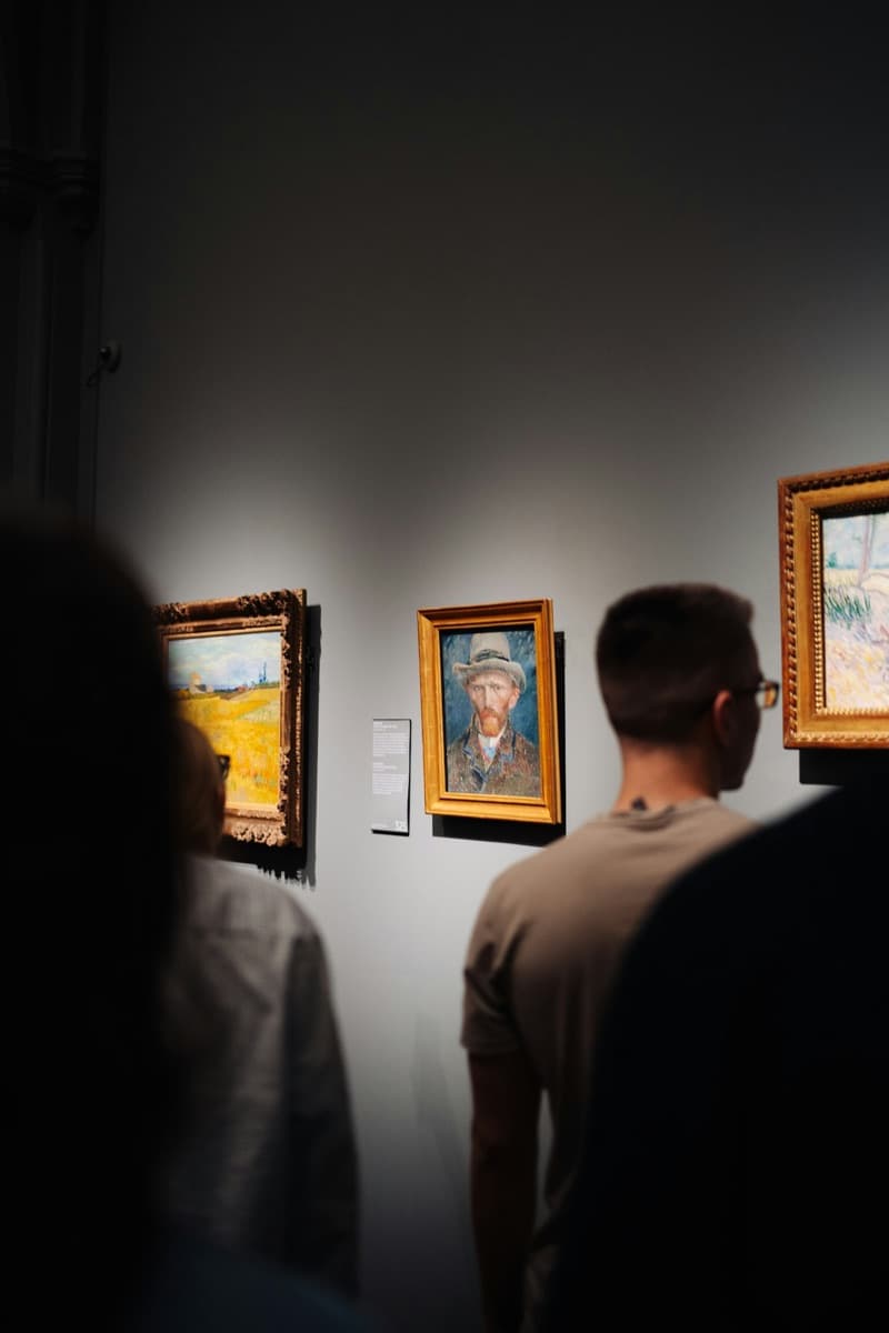 Gallery-goers in front of spotlit paintings